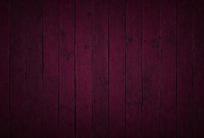 The primary subject of the image is a wooden floor with a purple tint. The setting is a room with a wooden floor, and the visual style is a close-up of the wooden floor. The colors and mood of the image are predominantly purple, creating a warm and inviting atmosphere.