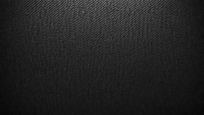 The primary subject of the image is a black leather material, which appears to be a leather-like fabric or a leather-like wallpaper. The setting is a black background, which contrasts with the leather material. The visual style is a close-up of the leather material, showcasing its texture and appearance. The colors and mood of the image are predominantly black, giving it a sleek and modern look.