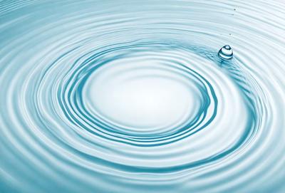 The primary subject of the image is a large, blue, rippling body of water. The water appears to be a deep blue, and it is surrounded by a clear blue sky. The setting is a serene, natural environment, with no visible land or structures. The visual style of the image is a photo, capturing the beauty of the water and its surroundings. The colors and mood of the image are calming and serene, with the deep blue water and the clear blue sky creating a peaceful atmosphere.