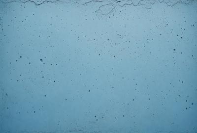The primary subject of the image is a blue wall with a pattern of white dots. The setting is a room with a blue background. The visual style is a close-up of the blue wall with white dots. The colors and mood of the image are predominantly blue and white, creating a calm and serene atmosphere.