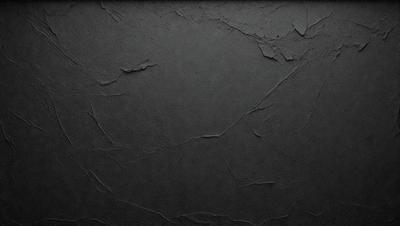 The primary subject of the image is a black background with a texture that resembles a wall or a piece of art. The setting is a dark room, and the visual style appears to be a close-up of the black background. The colors and mood of the image are predominantly dark and moody, with the black background being the main focus.