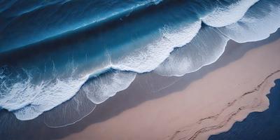 The primary subject of the image is a large wave crashing onto the beach. The setting is a beach with the ocean in the background. The visual style is a photo of the beach and ocean. The dominant colors are blue and white, with the blue representing the ocean and the white representing the wave. The overall atmosphere is dynamic and energetic, as the wave is crashing onto the beach.
