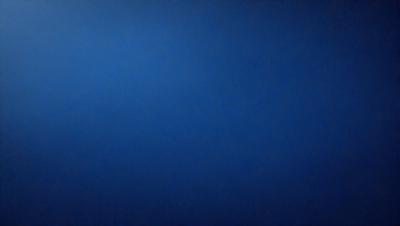 The primary subject of the image is a large, dark blue sky. The setting is a vast, open space with no visible landmarks or objects. The visual style is a natural, untouched landscape. The colors and mood are predominantly dark and moody, with the blue sky serving as the main focal point.