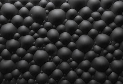 The primary subject of the image is a black background with a pattern of black and white balls. The setting is a dark room, and the visual style is a close-up of the balls. The dominant colors are black and white, and the overall atmosphere is a mix of modern and minimalist.