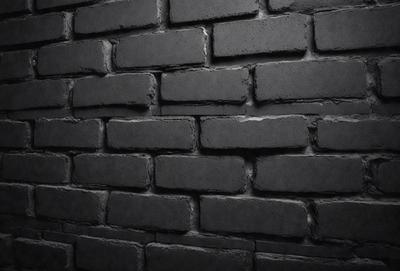 The primary subject of the image is a brick wall. The setting is a dark room, and the visual style is a black and white photo. The dominant colors are black and white, creating a moody atmosphere.