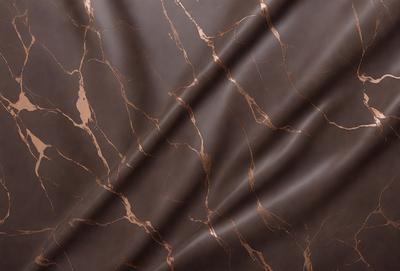 The primary subject of the image is a marble-like patterned fabric. The setting is a dark background, which contrasts with the fabric's pattern. The visual style is a close-up of the fabric, showcasing its intricate design. The colors and mood of the image are predominantly dark, with the fabric's pattern providing a sense of depth and texture.