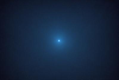 The primary subject of the image is a bright blue moon, which is the main focus of the scene. The moon is located in a dark, cloudy sky, creating a dramatic contrast between the bright moon and the surrounding darkness. The visual style of the image is a photo, capturing the beauty of the moon in its natural environment. The colors and mood of the image are predominantly dark and moody, with the bright blue moon standing out as the main source of light and interest.
