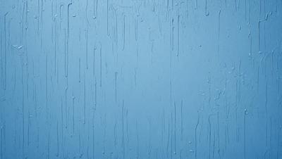 The primary subject of the image is a blue wall with water droplets on it. The setting is a room with a blue wall, and the visual style is a close-up of the wall. The colors and mood of the image are predominantly blue, with a slightly wet and moist appearance.
