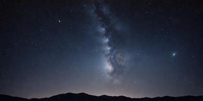 The primary subject of the image is the night sky filled with stars. The setting is a dark, star-filled sky, and the visual style is a photo. The colors and mood of the image are predominantly dark and serene, with the stars providing a sense of wonder and tranquility.