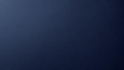 The primary subject of the image is a large, dark blue sky. The setting is a vast, open space with no visible landmarks or objects. The visual style is a simple, unadorned representation of the sky. The colors and mood are predominantly dark and moody, with the blue hue creating a sense of depth and vastness.