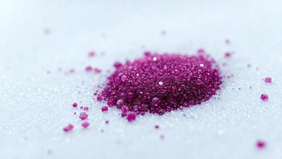 The primary subject of the image is a pink substance, possibly a powder or a liquid, that is spread out on a white surface. The setting appears to be a snowy environment, as the white surface resembles snow. The visual style of the image is a close-up, focusing on the pink substance. The colors in the image are predominantly pink, which gives the scene a warm and inviting atmosphere.