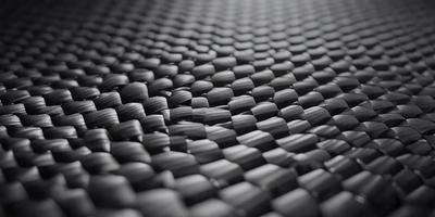 The primary subject of the image is a black and white patterned surface, which appears to be a woven or knitted material. The setting is a dark background, which contrasts with the patterned surface. The visual style is a close-up of the pattern, showcasing the intricate details of the design. The colors and mood of the image are predominantly dark and moody, with the black and white pattern adding a sense of depth and complexity to the scene.