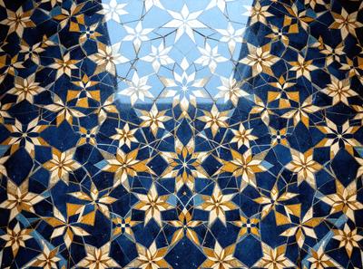 The primary subject of the image is a blue and gold mosaic tile floor. The setting is a room with a window, and the visual style is a close-up of the tile floor. The colors and mood of the image are vibrant and lively, with the blue and gold tiles creating a warm and inviting atmosphere.