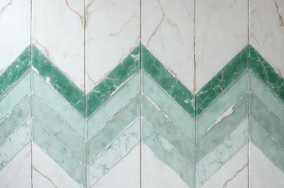 The image features a white and green marble wall with a patterned design. The wall is adorned with a series of white and green diamond shapes, creating a visually appealing and unique pattern. The combination of white and green marble and the intricate diamond pattern gives the wall a sophisticated and elegant appearance.