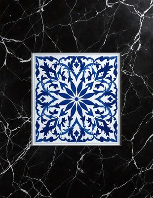 The primary subject of the image is a blue and white tile with a flower pattern. The tile is placed on a black marble countertop, which serves as the setting for the scene. The visual style of the image is a close-up of the tile, showcasing its intricate design. The dominant colors in the image are blue and white, creating a calm and elegant atmosphere.