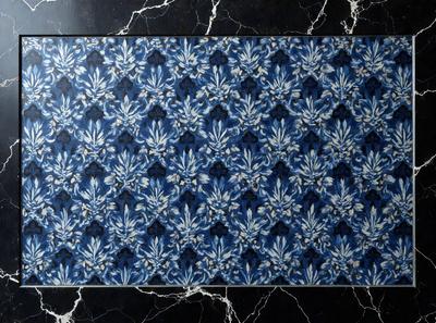 The primary subject of the image is a blue and white floral patterned tablecloth. The tablecloth is placed on a black marble table, which serves as the setting for the scene. The visual style of the image is a close-up of the tablecloth, showcasing its intricate design. The colors and mood of the image are predominantly blue and white, creating a calm and elegant atmosphere.