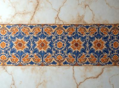 The primary subject of the image is a blue and orange tile with a pattern of flowers. The setting is a marble countertop, and the visual style is a close-up of the tile. The dominant colors are blue and orange, creating a vibrant and lively atmosphere.