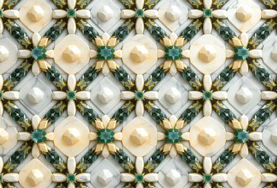 The primary subject of the image is a marble tile with a green and yellow pattern. The setting is a wall, and the visual style is a close-up of the tile. The colors and mood of the image are vibrant and lively, with the green and yellow colors creating a warm and inviting atmosphere.