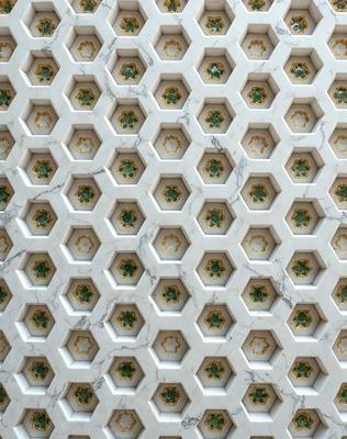 The primary subject of the image is a marble wall with a pattern of green and yellow circles. The setting is a room with a marble wall, and the visual style is a close-up of the wall. The dominant colors are green and yellow, creating a warm and inviting atmosphere.