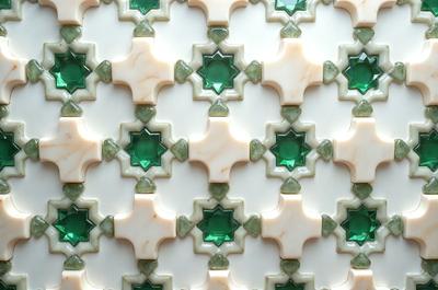 The primary subject of the image is a white and green tile with a pattern of stars and diamonds. The setting is a wall, and the visual style is a close-up of the tile. The colors and mood of the image are predominantly white and green, creating a clean and fresh atmosphere.