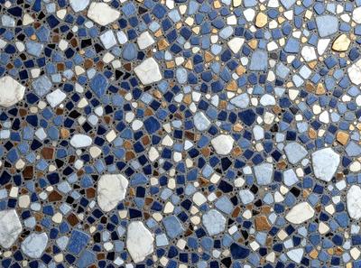 The primary subject of the image is a blue and gold mosaic tile. The setting is a wall with a blue and gold patterned tile. The visual style is a close-up of the tile, showcasing its intricate design. The colors and mood of the image are vibrant and lively, with the blue and gold tiles creating a visually appealing and inviting atmosphere.
