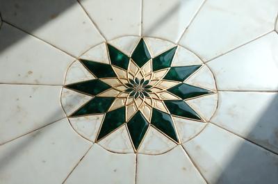 The primary subject of the image is a green and gold star pattern, which is the main object, scene, or focus of the image. The setting or background of the image is a white tile floor, and the visual style appears to be a combination of photo and digital art. The colors and mood of the image are predominantly green and gold, creating a warm and inviting atmosphere.