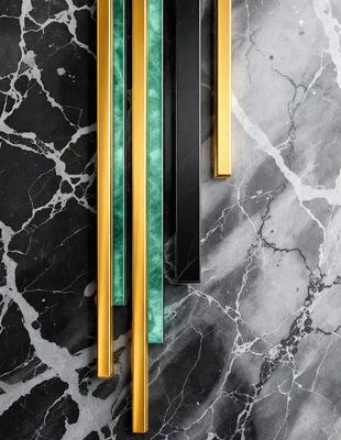 The primary subject of the image is a row of three different colored strips of material, which are placed on a black and white marbled surface. The setting is a countertop or a similar surface, and the visual style appears to be a close-up of the strips. The colors and mood of the image are predominantly black and white, with the three different colored strips adding a touch of contrast and visual interest.