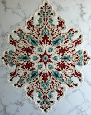 The primary subject of the image is a large, intricately designed, colorful, and ornate pattern. The pattern is displayed on a marble surface, which serves as the setting or background. The visual style of the image is a combination of photo and digital art, creating a unique and eye-catching design. The colors and mood of the image are vibrant and lively, with a focus on the red, green, and blue hues that make up the pattern.