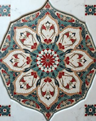 The primary subject of the image is a beautifully designed tile floor with a blue and red color scheme. The floor features a large, intricate design that includes a central flower, surrounded by other decorative elements. The setting is indoors, likely in a room with a marble surface. The visual style of the image is a combination of photo and digital art, creating a vibrant and eye-catching display. The colors and mood of the image are lively and inviting, with the blue and red tones ev
