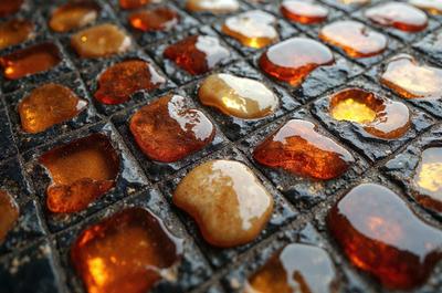 The primary subject of the image is a close-up of a tile floor with a pattern of yellow and orange tiles. The setting is an outdoor area with a stone floor. The visual style is a photo, and the colors and mood are warm and inviting.