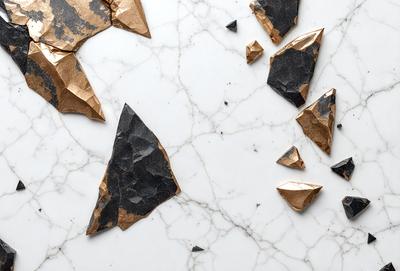 The primary subject of the image is a marble countertop with various pieces of paper, including a piece of gold paper, scattered across it. The setting is a white marble countertop, and the visual style appears to be a combination of photo and digital art. The colors and mood of the image are predominantly white, with the gold paper adding a touch of warmth and contrast.