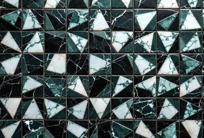 The primary subject of the image is a black and white tile pattern. The setting is a wall with a black and white tile pattern. The visual style is a pattern, and the colors and mood are predominantly black and white.