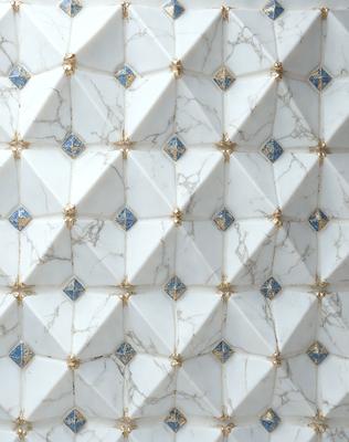 The primary subject of the image is a white marble wall with a pattern of blue diamonds. The setting is a room with a white marble wall, and the visual style is a close-up of the wall. The colors and mood of the image are predominantly white and blue, creating a clean and elegant atmosphere.