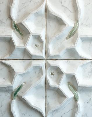 The primary subject of the image is a white marble wall with a pattern of hexagons. The setting is a room with a white marble countertop. The visual style is a photo of the marble wall and countertop. The dominant colors are white and gray, creating a clean and elegant atmosphere.