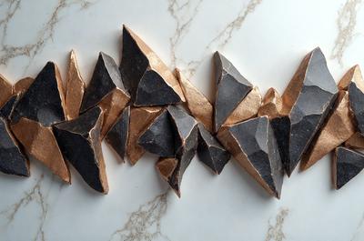 The primary subject of the image is a collection of oddly shaped, black and gold sculptures. These sculptures are arranged in a visually appealing manner, creating a unique and artistic display. The setting is a white marble countertop, which serves as a striking backdrop for the sculptures. The visual style of the image is a combination of digital art and illustration, showcasing the intricate details and craftsmanship of the sculptures. The colors and mood of the image are predominantly black