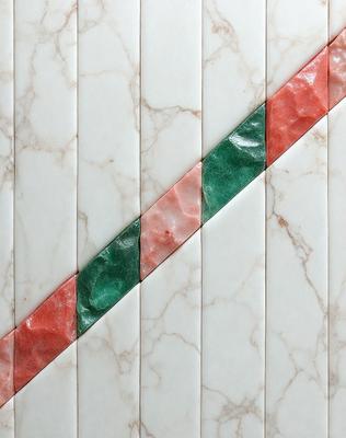 The primary subject of the image is a marble tile with a green and red striped pattern. The setting is a marble wall, and the visual style is a close-up of the tile. The colors and mood of the image are predominantly green and red, creating a vibrant and eye-catching pattern.