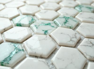 The primary subject of the image is a white marble tile with a green accent. The setting is a white tile floor, and the visual style is a close-up of the tile. The colors and mood of the image are predominantly white and green, creating a clean and fresh atmosphere.