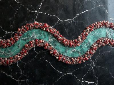 The primary subject of the image is a green and red striped piece of artwork, possibly a sculpture or a decorative item. The setting is a black marble surface, which serves as the background for the artwork. The visual style of the image is a close-up, showcasing the intricate details of the piece. The dominant colors in the image are green and red, creating a vibrant and eye-catching appearance.