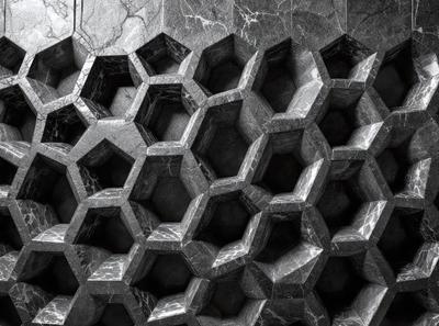 The primary subject of the image is a large, intricate stone wall with a pattern of hexagons. The setting is a dark room, and the visual style appears to be a black and white photo. The colors and mood of the image are predominantly dark and moody, with the stone wall serving as the focal point.