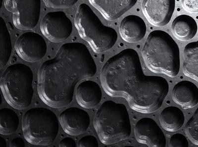 The primary subject of the image is a close-up of a black and white patterned surface, which appears to be a piece of machinery or a textured wall. The setting is a black background, which contrasts with the patterned surface. The visual style is a close-up, which emphasizes the intricate details of the pattern. The colors and mood of the image are predominantly black and white, giving it a classic and timeless feel.