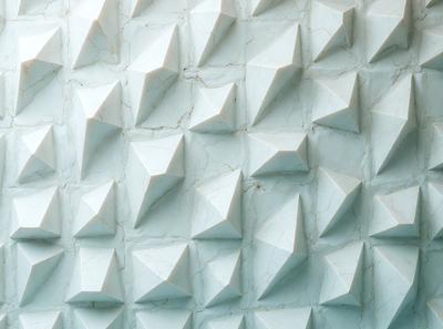 The primary subject of the image is a wall with a pattern of white triangles. The setting is a room with a blue background, giving the wall a unique and visually appealing appearance. The visual style of the image is a combination of photo and digital art, creating a striking and modern design. The dominant colors are white and blue, with the white triangles contrasting against the blue background, creating a sense of depth and dimension.