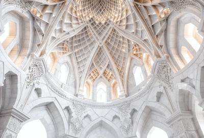 The primary subject of the image is a large, ornate, and intricate stone ceiling. The setting is a cathedral, and the visual style is a combination of photo and digital art. The ceiling features a unique design with a large, open, and airy structure. The colors and mood of the image are predominantly white, giving it a clean and serene atmosphere.