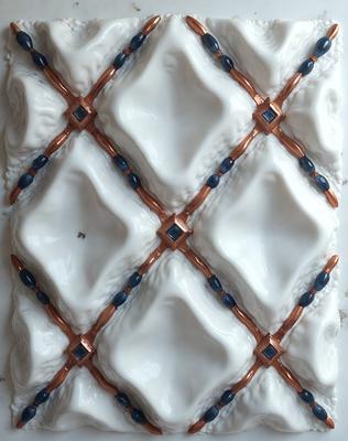The primary subject of the image is a white and blue ceramic tile with a pattern of blue beads. The tile is part of a larger design, possibly a wall or a floor. The setting is indoors, with the tile being the main focus of the image. The visual style is a close-up of the tile, showcasing its intricate design and craftsmanship. The colors and mood of the image are predominantly white and blue, creating a clean and soothing atmosphere.