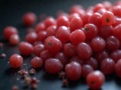 The primary subject of the image is a pile of red berries, which are the main focus of the scene. The berries are displayed on a black surface, giving the image a modern and minimalist visual style. The colors of the berries are predominantly red, creating a vibrant and lively atmosphere.