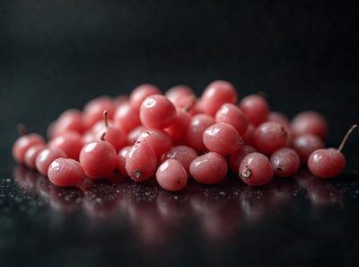 The primary subject of the image is a pile of red berries, which are the main focus of the scene. The berries are placed on a black surface, which serves as the background. The visual style of the image is a close-up of the berries, showcasing their details and texture. The colors of the berries are predominantly red, creating a vibrant and lively atmosphere.