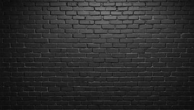 The primary subject of the image is a brick wall. The setting is a dark room, and the visual style is a black and white photo. The dominant colors are black and white, creating a moody atmosphere.