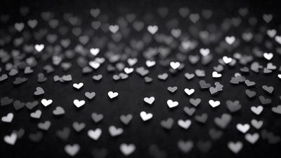 The primary subject of the image is a collection of silver hearts scattered across a black background. The hearts are arranged in various positions, creating a visually appealing pattern. The setting is a dark background, which contrasts with the shiny silver hearts, giving the image a striking and eye-catching visual style. The overall atmosphere is one of elegance and sophistication, as the hearts are the main focus of the image.