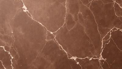 The primary subject of the image is a marble wall with a brown color. The setting is a room with a brown surface, possibly a countertop or a wall. The visual style is a close-up of the marble wall, showcasing its texture and details. The colors and mood of the image are warm and natural, with the brown marble and the brown surface creating a sense of warmth and earthiness.