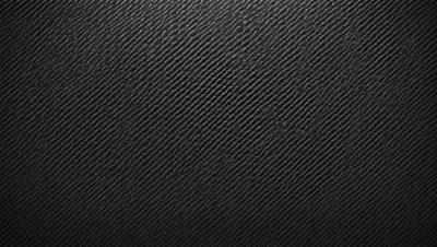 The primary subject of the image is a black leather material, which appears to be a leather-like fabric or a leather-like pattern. The setting is a black background, which contrasts with the leather material. The visual style is a close-up of the leather material, showcasing its texture and pattern. The colors and mood of the image are predominantly black, giving it a sleek and modern appearance.