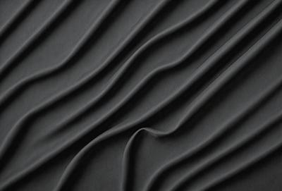 The primary subject of the image is a close-up of a black and gray patterned surface, which appears to be a textured fabric or a wall with a unique design. The setting is a dark room, which adds to the overall mood of the image. The visual style is a close-up, focusing on the intricate details of the pattern. The colors and mood of the image are predominantly dark and moody, with the black and gray pattern creating a sense of depth and complexity.